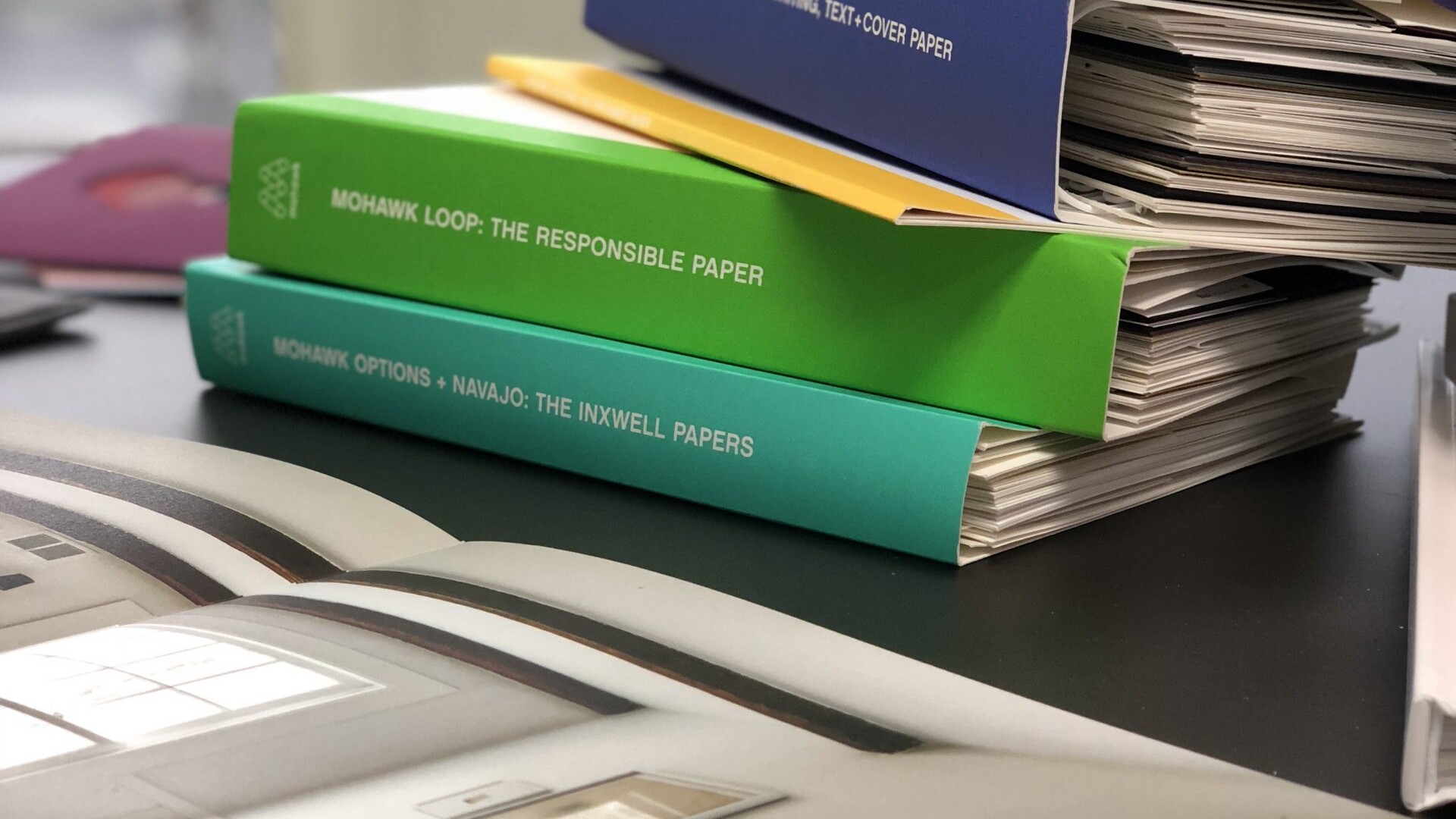 A stack of binders sit on a desk.