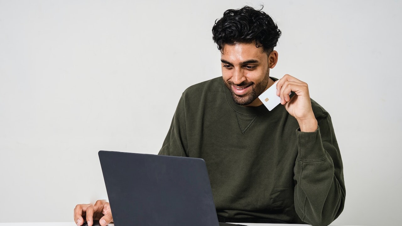 Person with card in hand purchasing online and happy with user satisfaction