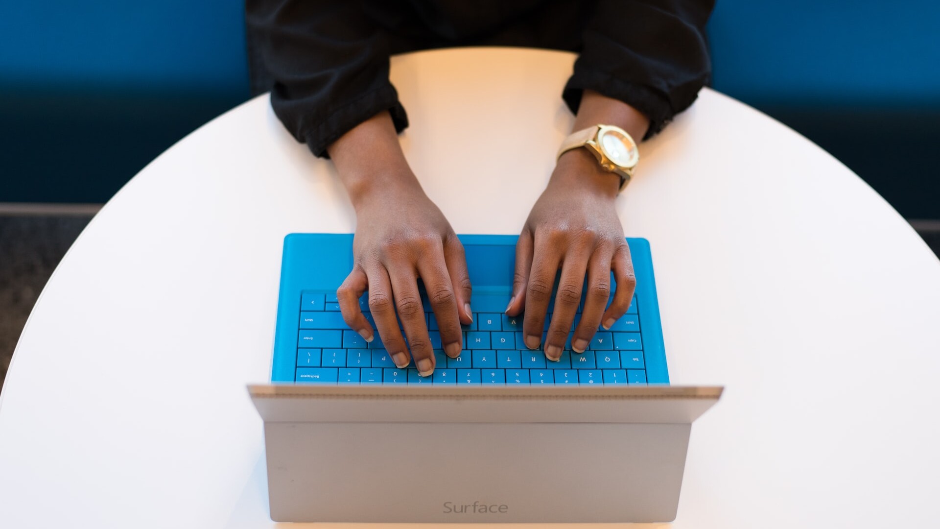 User working on laptop with a blue keyboard.