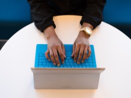 User working on laptop with a blue keyboard.