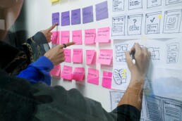 Designers working on the user experience as they brainstorm on a whiteboard.