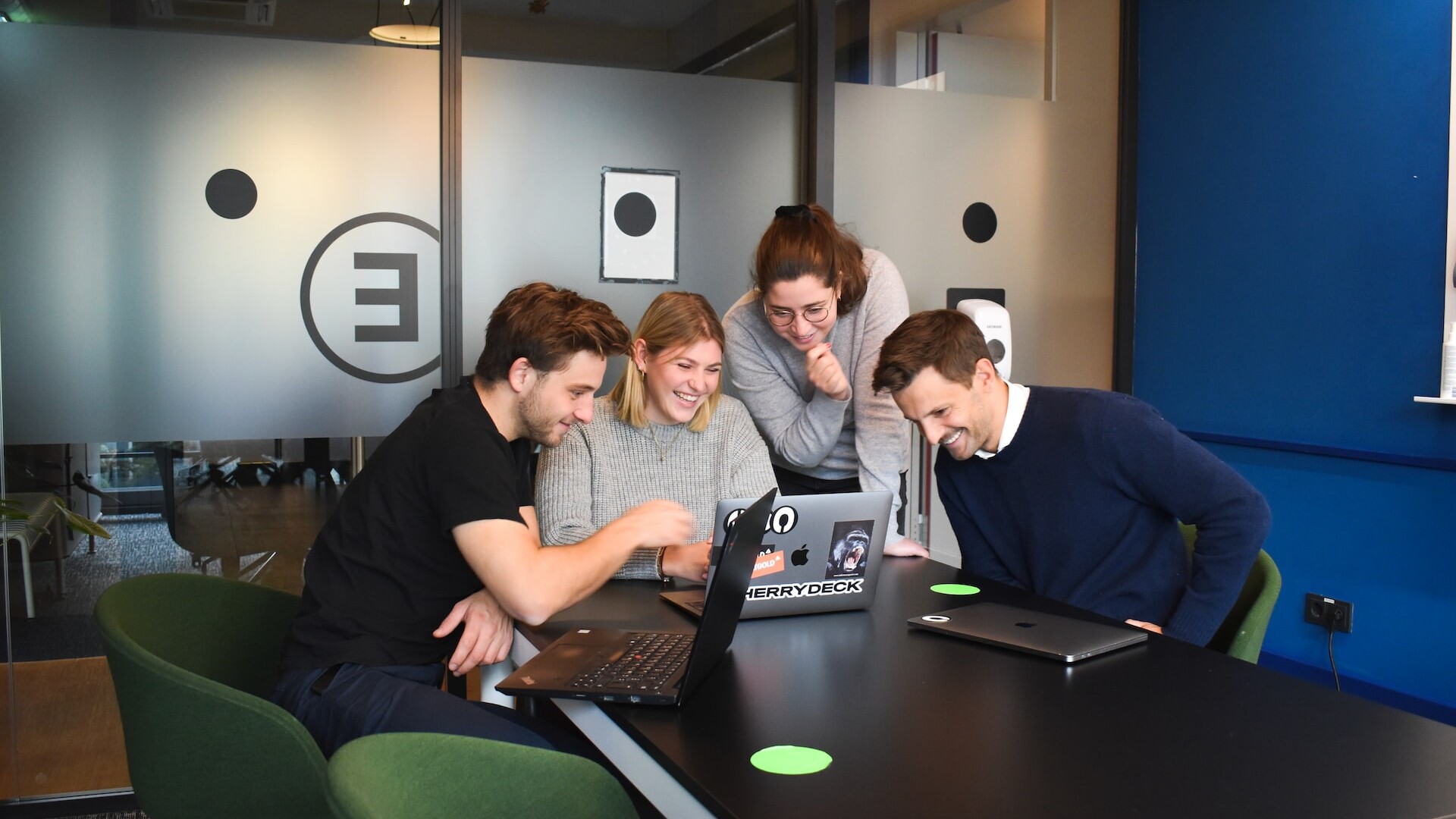 people working on a laptop together while smiling.