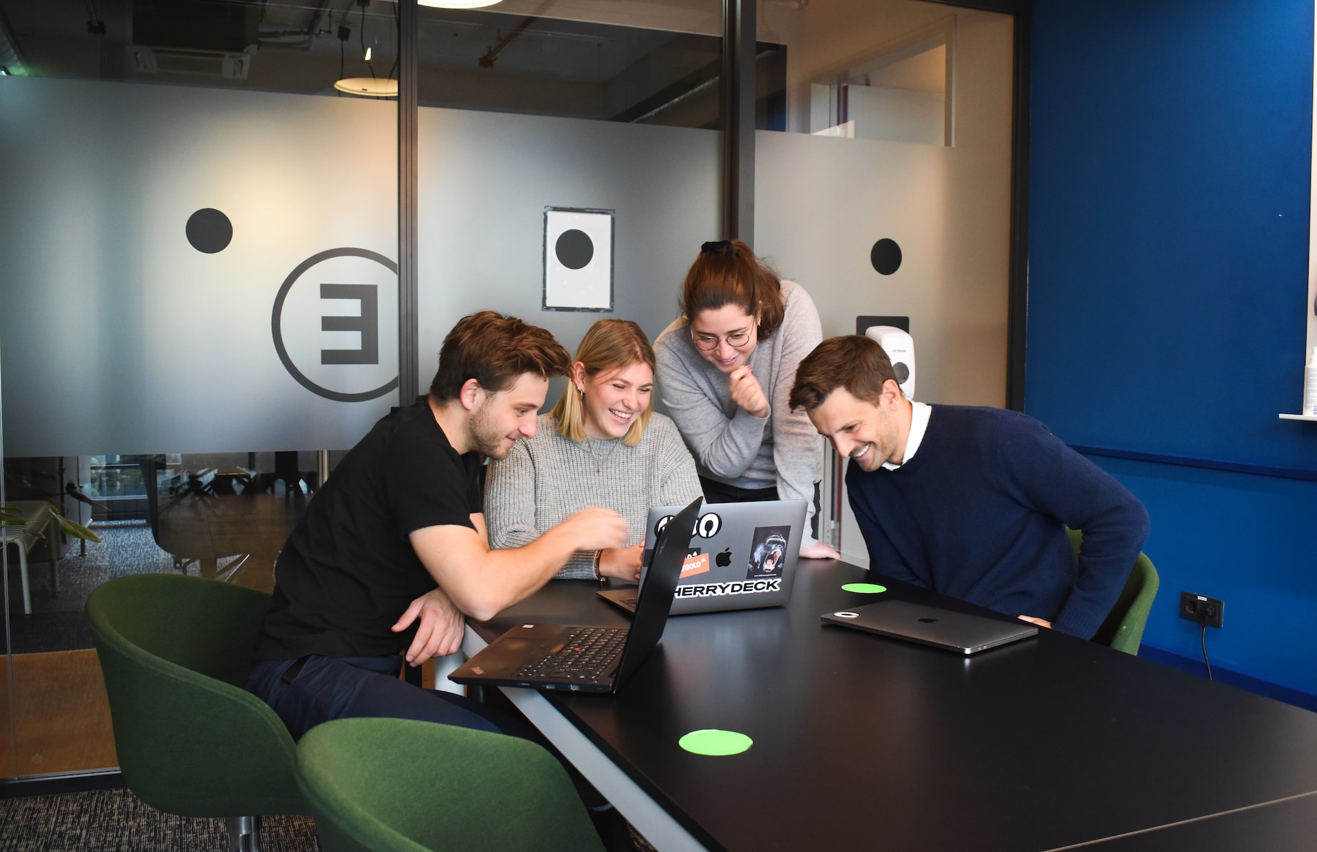 people working on a laptop together while smiling.