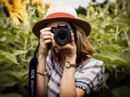 Person holding a camera in a sunflower field.