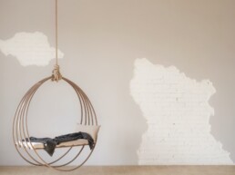 A swinging chair hangs alone in a room.