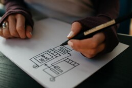 A UI designer creates a responsive wireframe with pen and paper.