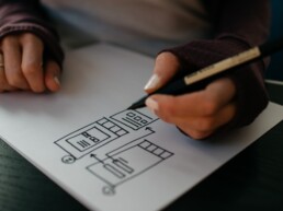 A UI designer creates a responsive wireframe with pen and paper.