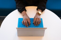 A person typing on laptop with a blue keyboard.