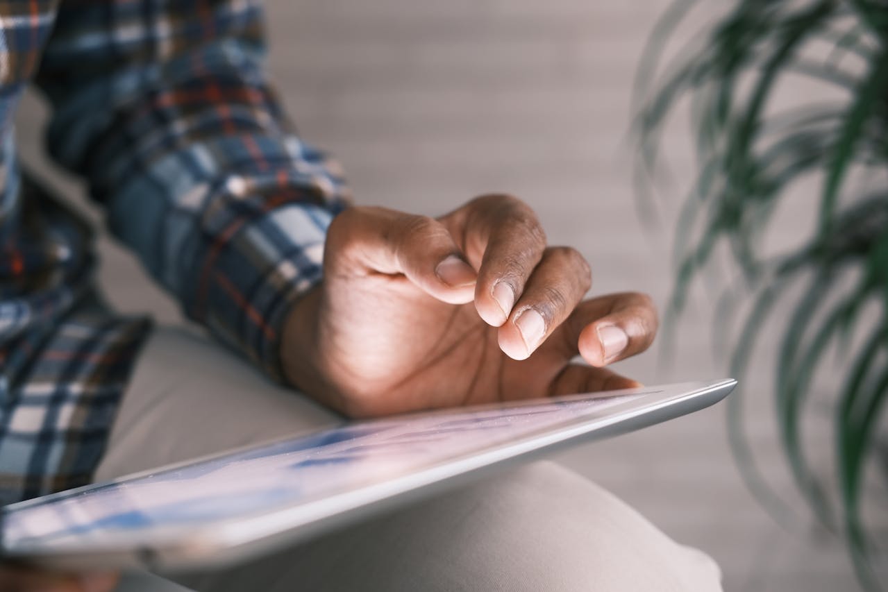 Close-up of a person using a tablet, tapping the screen with one finger, illustrating intuitive touch interaction in a digital interface.